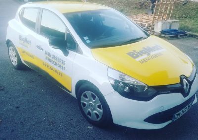 Marquage jaune et blanc sur une Renault Clio pour BigMat Menuiserie Ardéchoise à Lavilledieu, avec capot entièrement floqué