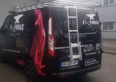 Covering complet d'un Ford Transit noir pour R·Forge à Joyeuse, avec logo, dinosaure rouge géométrique et coordonnées de l'entreprise