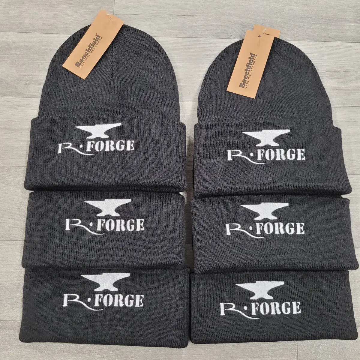 Six bonnets anthracite brodés du logo R-Forge en fil blanc, disposés à plat en deux colonnes