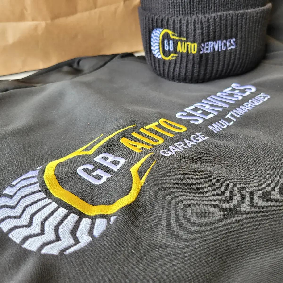 Veste de travail noire et bonnet assorti, brodés du logo GB Auto Services en jaune et gris