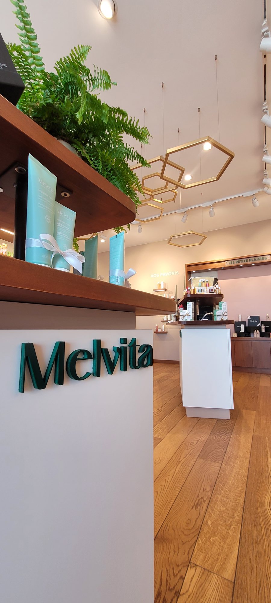Comptoir d accueil de la boutique Melvita apres habillage, facade blanche et logo en relief