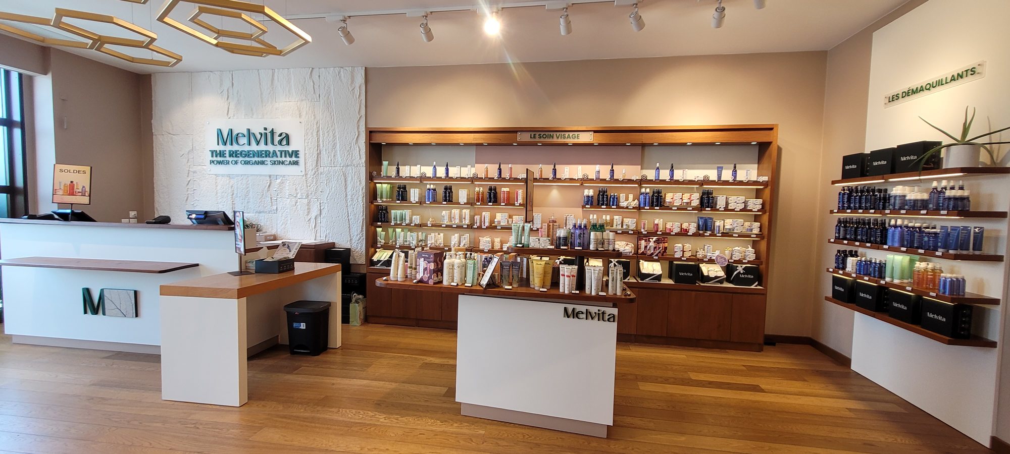 Boutique de cosmetiques Melvita a Aubenas apres habillage interieur : rayonnages clairs, comptoirs blancs et sol bois