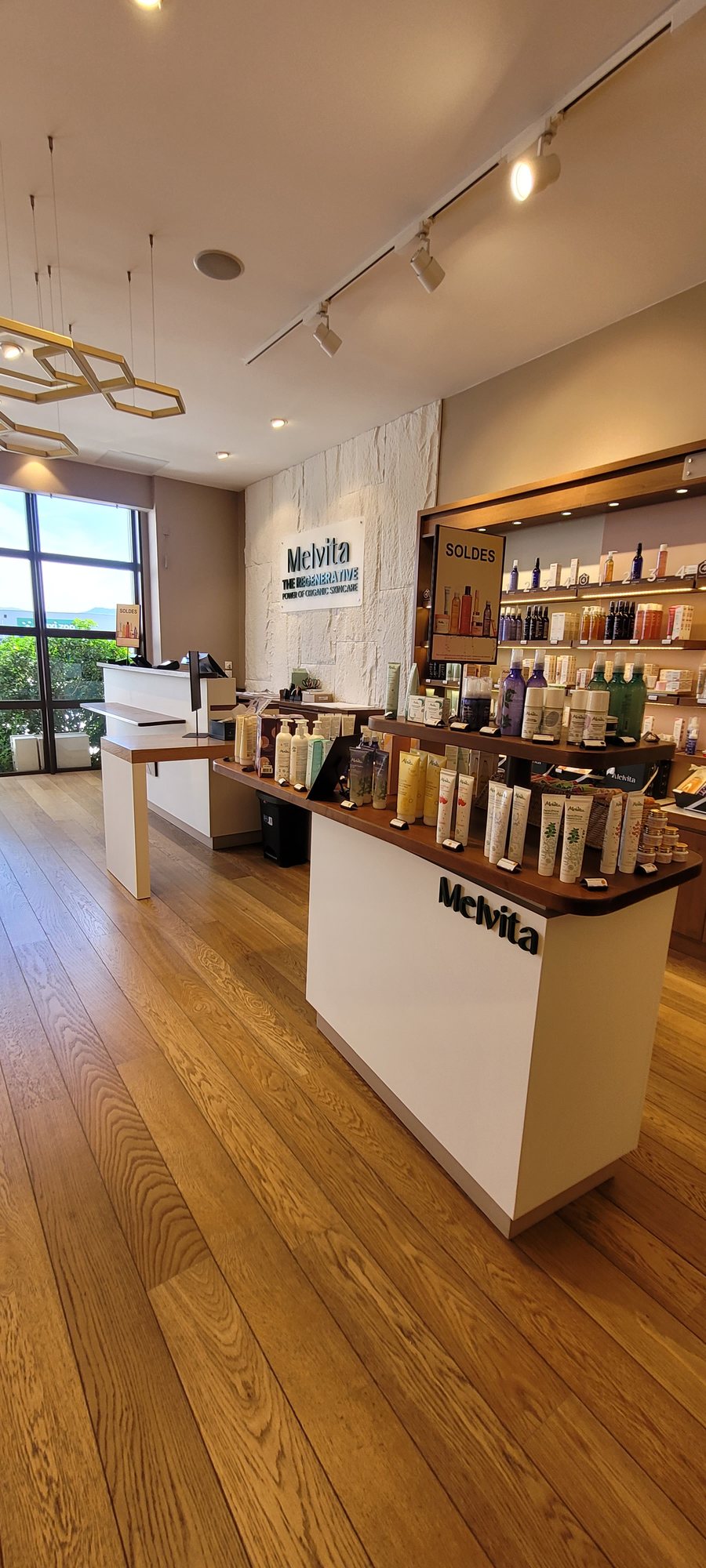 Rayonnages de la boutique Melvita apres habillage, sol en bois clair et meubles blancs