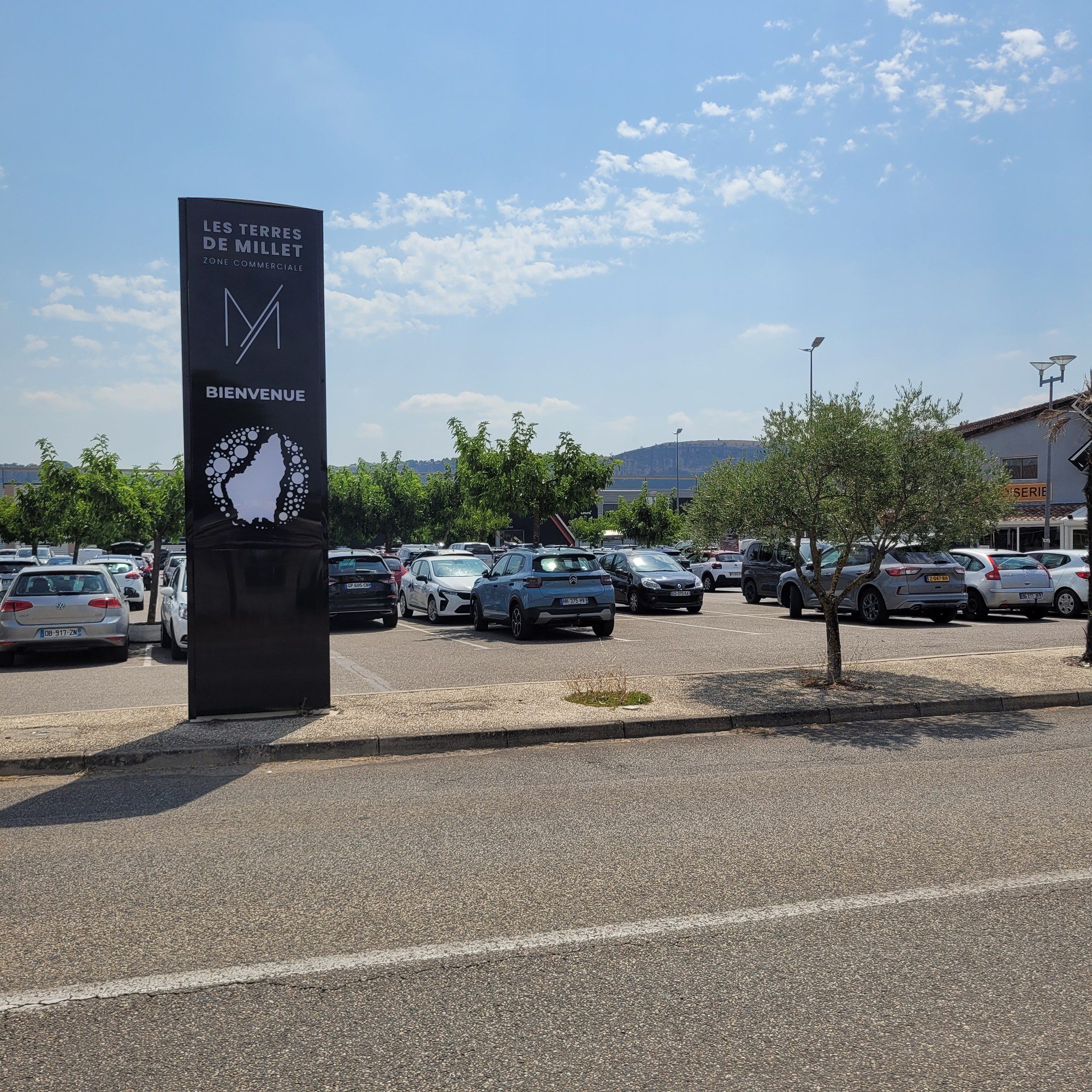 Totem noir de la zone commerciale Les Terres de Millet, dressé en bordure du parking