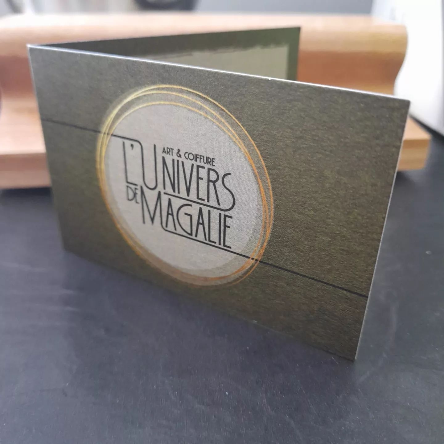 Carte de visite pliée du salon L'Univers de Magalie, art et coiffure, dorure or sur papier texturé kaki