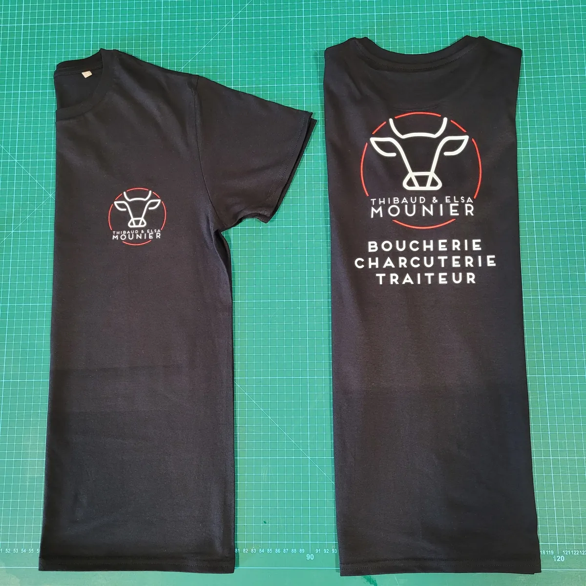 Deux tee-shirts noirs imprimés du logo Boucherie Mounier, petit format sur la poitrine et grand format dans le dos